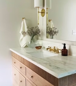 Bathroom vanity with marble-look countertop and gold fixtures