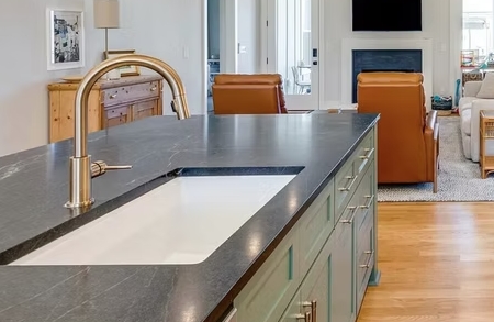 Kitchen sink set into a dark countertop on a green island