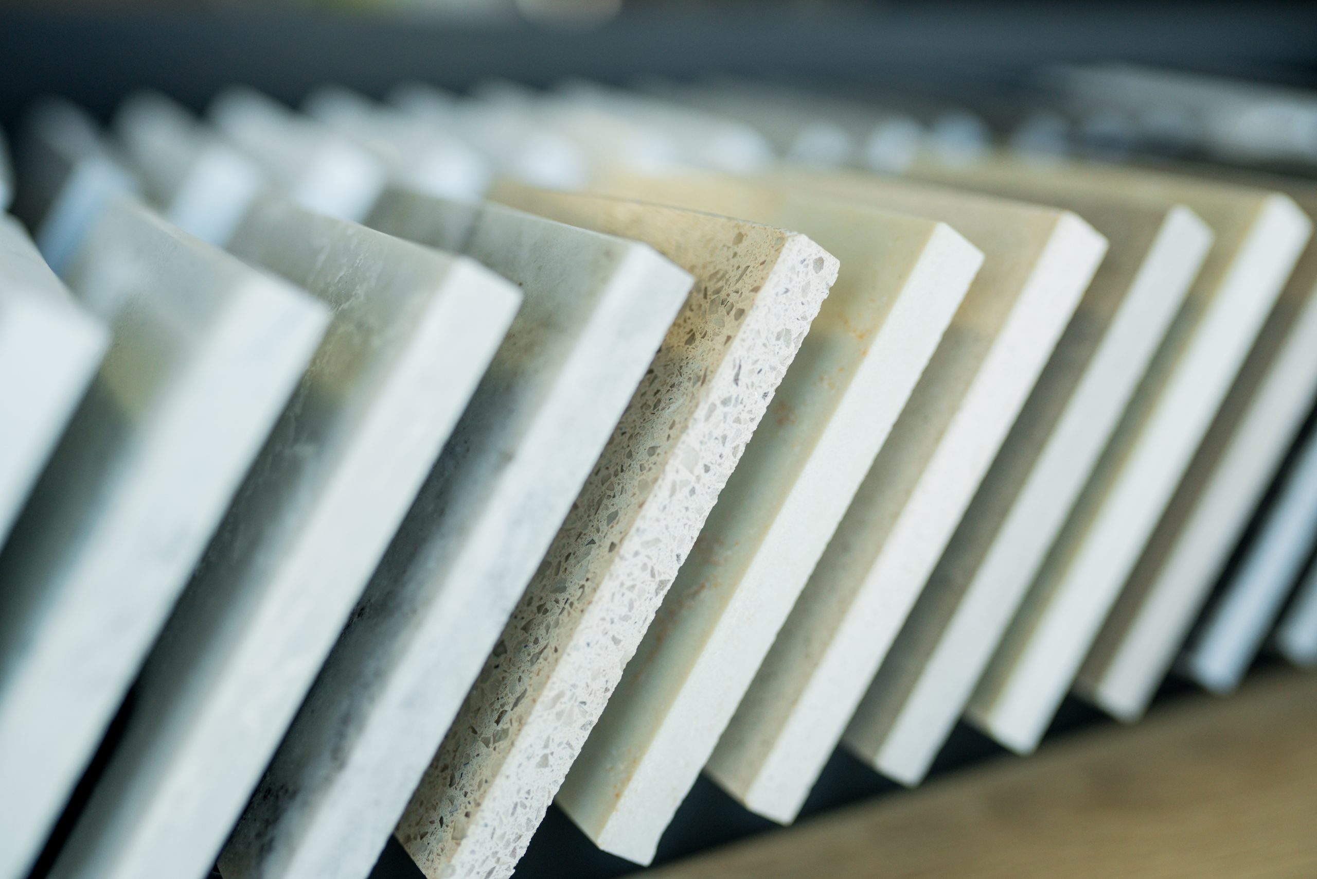 Close-up of stone countertop samples in a Nashville showroom showing a row of marble, quartz, and granite slab edges as a homeowner compares materials.