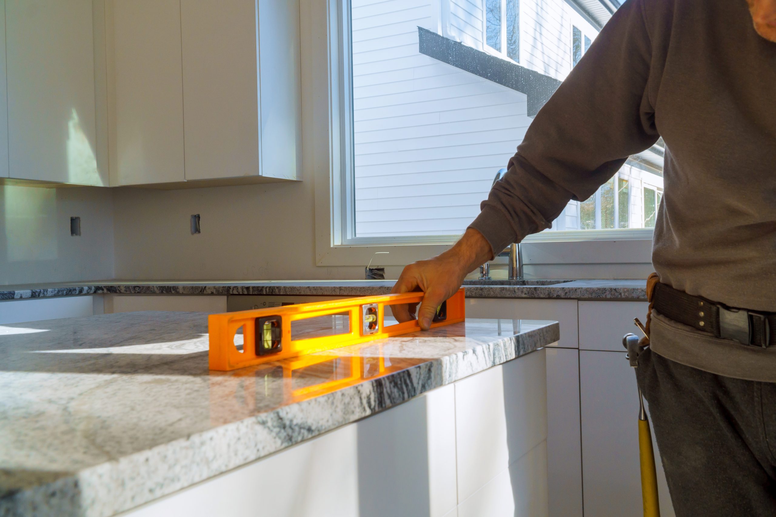 Countertop fabricator checking the level of a freshly installed granite slab in a home kitchen during a Nashville-area countertop install.