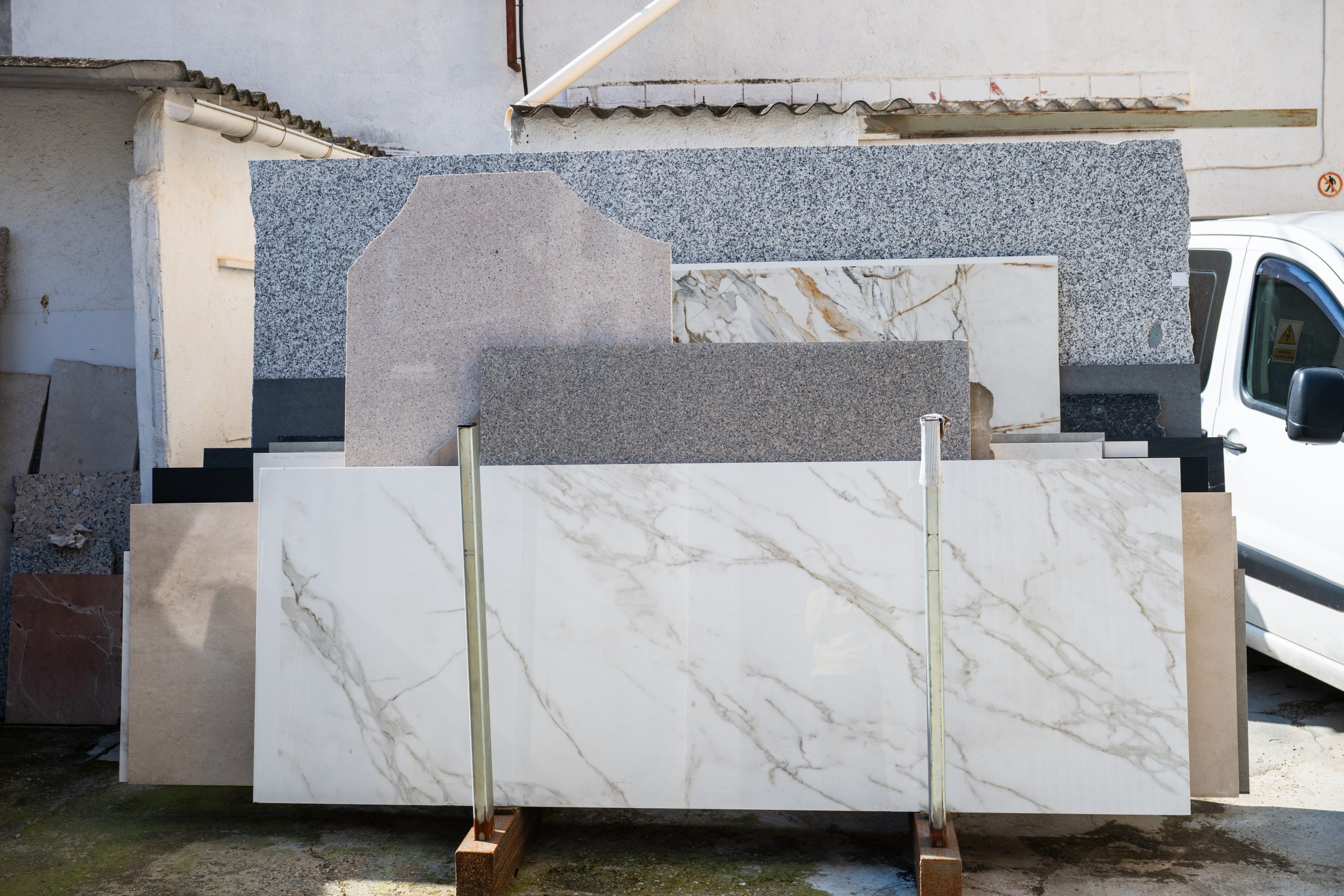 Granite and marble countertop slabs standing outdoors in a stone yard, showing the natural stone materials compared for outdoor kitchen countertops.