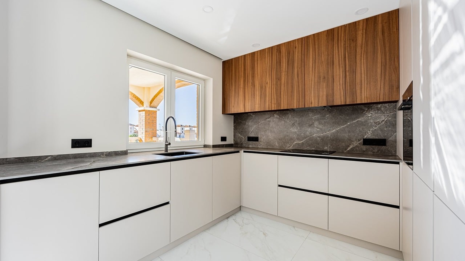 Modern kitchen with a gray natural-stone slab backsplash running up the wall to match the stone countertop