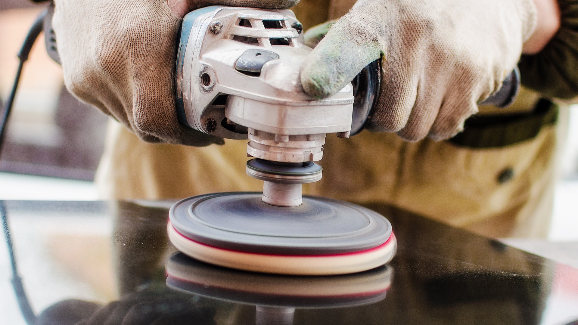 A worker installing a kitchen faucet into a newly set granite countertop during a countertop installation.