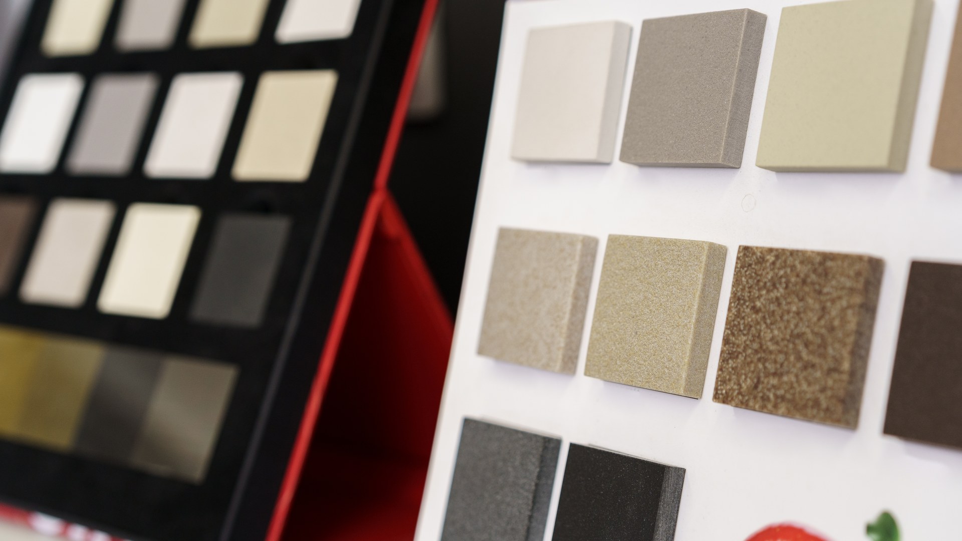 Engineered quartz countertop sample chips in neutral and grey tones displayed on a fabricator's selection board